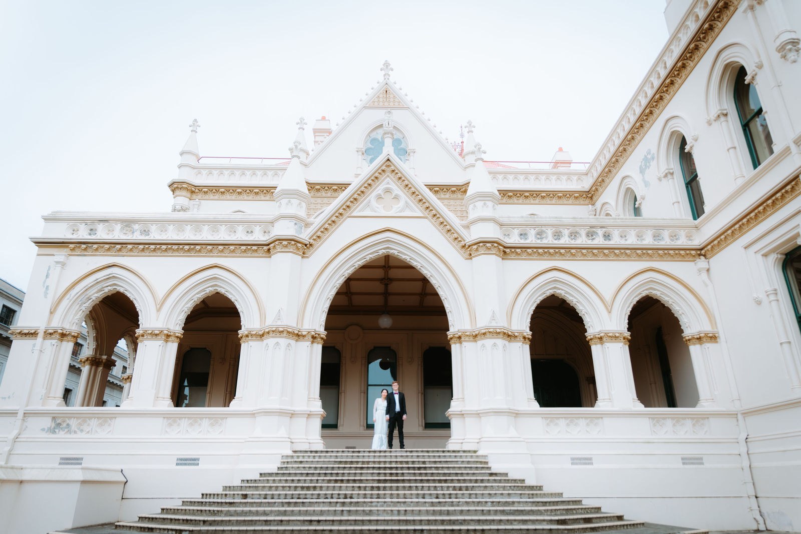A wedding couple beneath the Gothic archway of the Parliamentary Library in Wellington, New Zealand