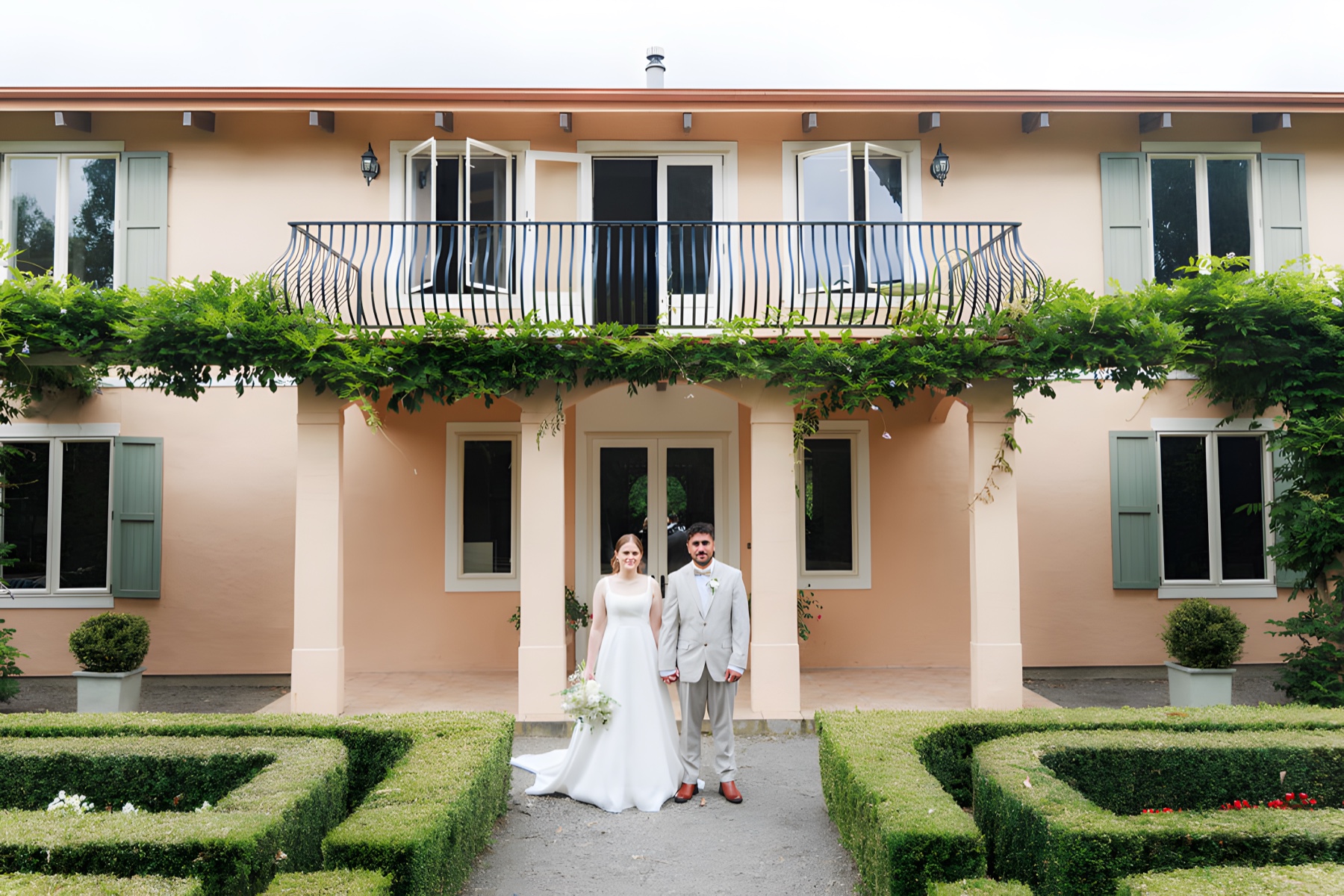 A wedding couple in front of Villa Candotti, an Italian garden wedding venue near Palmerston North